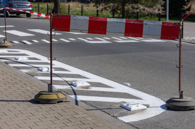 Trafik kuruluşu ve güvenliğinin geliştirilmesi sırasında yerleşim sokağında geçici bariyerle yeni boyanmış yol işaretleri. Kentsel altyapı güncellemesi ve yaya alanı düzenlemesi