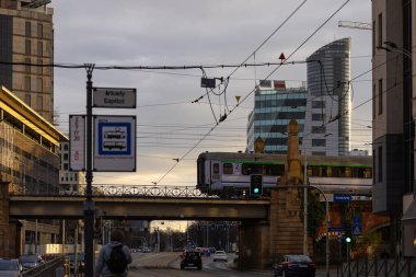 Wroclaw, Polonya-Marth 30, 2025: Günbatımında şehir merkezinde modern cam gökdelenler ve tarihi demiryolu köprüsü kentsel tramvay durakları ve elektrik kabloları ile. Mimari karşıtlık, altyapı ve kentsel planlama