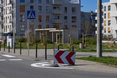 Güneşli bahar günlerinde modern konut binalarının yakınında yaya geçidi ve yol inşaat bariyerleri olan şehir güvenliği bölgesi. Yol işaretleme güncellemeleri, trafik kontrolü ve şehir altyapısı