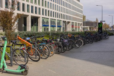 Wroclaw, Polonya-13 Nisan 2025: Sürdürülebilir ulaşım ve sağlıklı yaşam tarzını destekleyen modern ofis binasının önüne park edilmiş bisiklet ve elektrikli scooter. Kentsel hareketlilik ve ekolojik yaşam