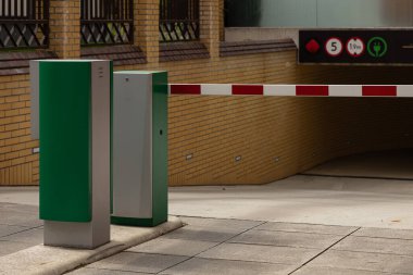 Modern yeraltı otoparkına otomatik giriş engeli güvenlik sistemi, elektrikli araç şarj levhası ve boy sınırlama sembolü. Şehir altyapısı ve akıllı park teknolojisi