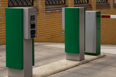 Yeraltı otoparkının girişinde yeşil bilet makinesi ve bariyer kapısı olan modern otomatik erişim kontrol sistemi. Akıllı şehir altyapısı ve park teknolojisi