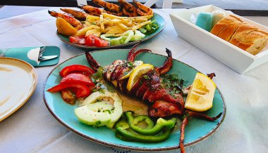 Kızarmış, doldurulmuş, karides, kızarmış patates ve dilimlenmiş sebzeler, limon dilimleri ve sıcak ekmekle servis edilen bir tabak. Öğle yemeğinde iştah açıcı ana yemek. Akrotiri, Santorini 'deki büfe.