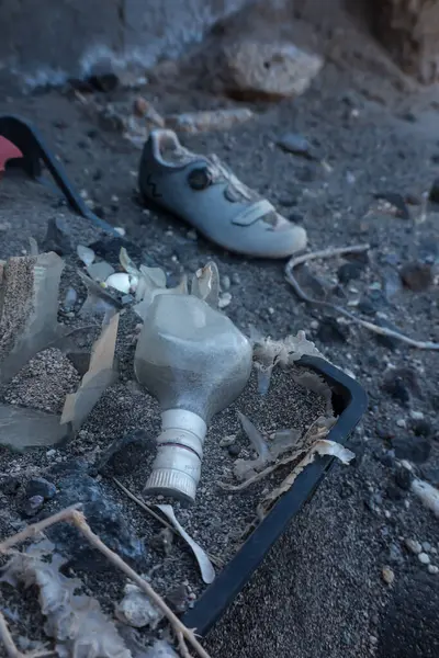 Yerde bir şişe alkol, bir çift ayakkabının yanında. Şişe kırılmış ve ayakkabılar kirlenmiş. Olay yeri ıssız ve terk edilmiş.