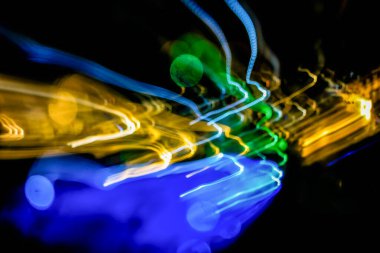 Gece vakti yüzme havuzunun uzun pozlu bir görüntüsü karanlık bir karanlık gece gökyüzüne doğru dönen soyut ışık izlerini yakalar.