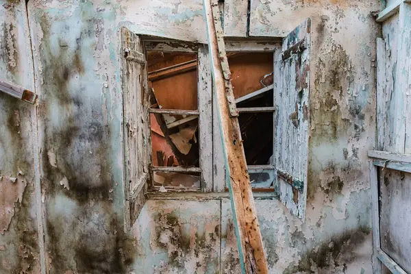 Paragkes Beach, Vouliagmeni, Atina 'da terk edilmiş bir barakanın harap olmuş ahşap duvarındaki kırık pencere çerçevesi.