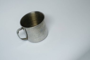 Gri arka planda içki içmek için gümüş metal bardak