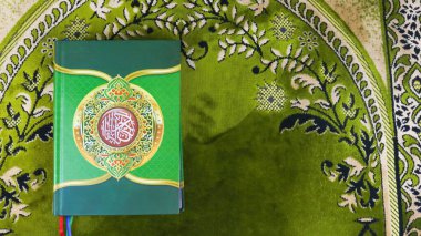 The Holy Qur'an on a green prayer mat. clipart