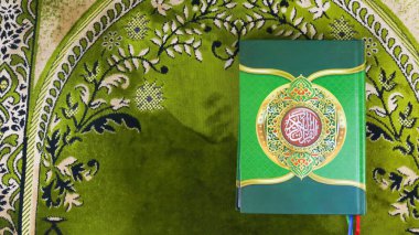 Yeşil bir paspasın üzerinde Kuran-ı Kerim.