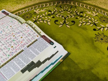 Yeşil bir paspasın üzerinde Kuran-ı Kerim.
