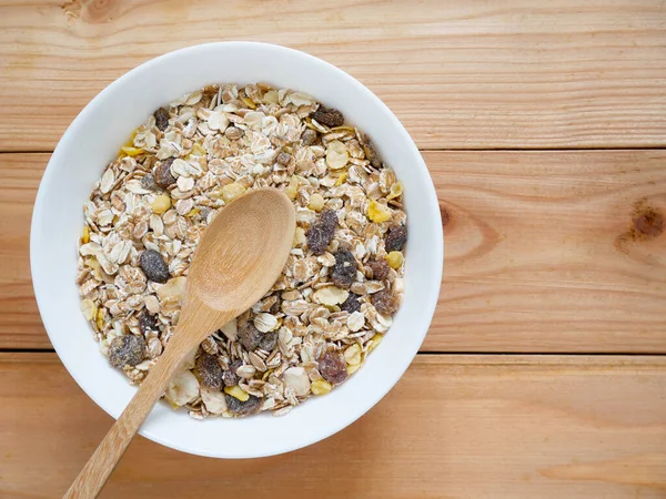 A Bowl of muesli breakfast and rolled oats with dried fruits on wooden table. Top view.