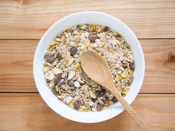 A Bowl of muesli breakfast and rolled oats with dried fruits on wooden table. Top view.