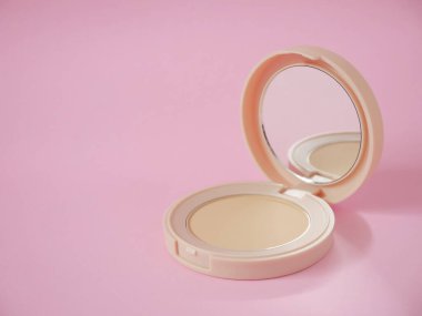 Bej çantalı yüz pudrası ve pembe arka planda fotokopi alanı. Pudra temeli, pudra makyajı..