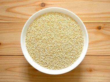 Bir kase çiğ beyaz Quinoa ahşap masa üzerinde. Üstten görünüm.