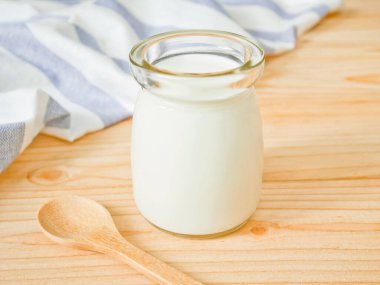 Ahşap masa üzerinde sade yoğurt bir kavanoz. Sağlıklı gıda kavramı.