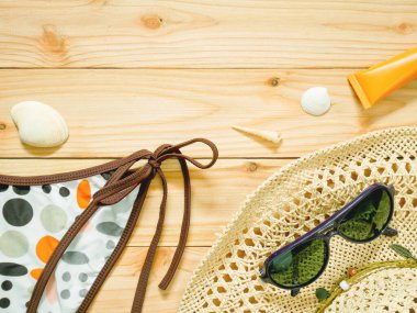 Bikini altları, güneş gözlüğü, plaj şapka ve güneş koruyucu kopya alanı ile ahşap arka plan üzerinde. Bayan beachwear aksesuarlar deri ve gözleri güneşten korumak için. Yaz tatil kavramı.