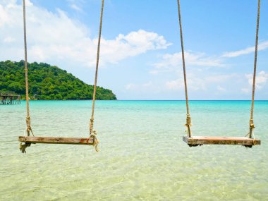 Tahta salıncaklar denizin üzerinde asılı.