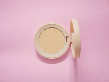 Pembe arka planda bej çantalı yüz pudrası. Pudra temeli, pudra tozu makyajı. Üst görünüm.