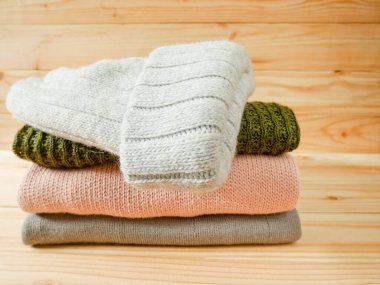 Ahşap arka planda kazak ve örgü kapak yığını. Kış giysileri kavramı.