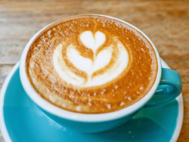 Bir fincan kahve latte sanat kafede ahşap masa üzerinde buharda pişmiş süt ile