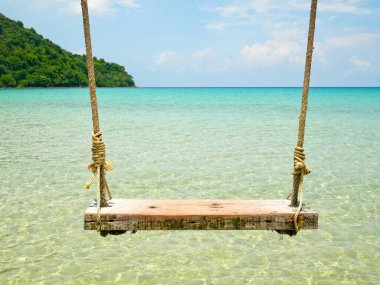 Tahta salıncak denizin üzerinde asılı.