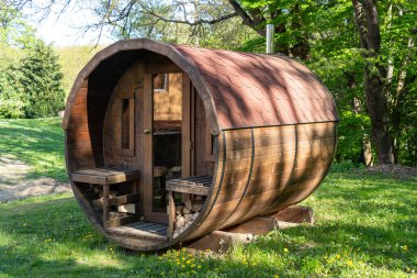 Sonbahar güneşinde yeşil bir ormanın kenarındaki açık kahverengi sauna binası.