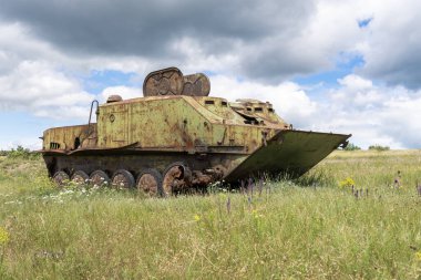 Rusty old soviet military vehicle wreck in a field clipart