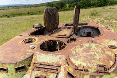 Rusty old soviet military vehicle wreck in a field clipart