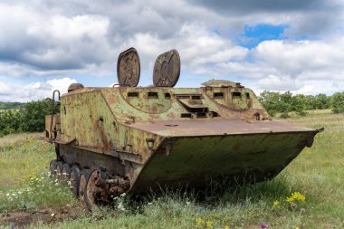 Rusty old soviet military vehicle wreck in a field clipart