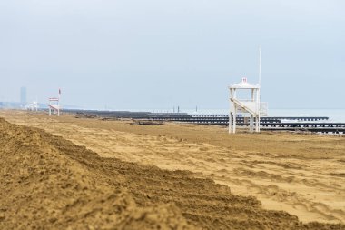 İtalya 'da sonbaharda cankurtaran kuleleri ve ahşap iskeleleri olan terk edilmiş bir sahil.