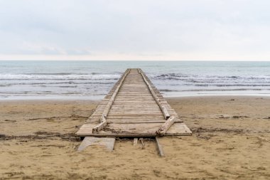 Adriyatik Denizi 'ne çıkan tahta iskele İtalya' da bulutlu bir sonbahar plajında.
