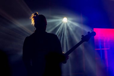 Gitarist erkek silueti konserde arka planda.