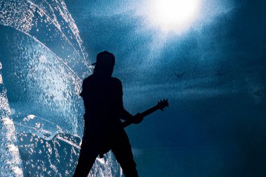 Gitarist erkek silueti konserde arka planda.