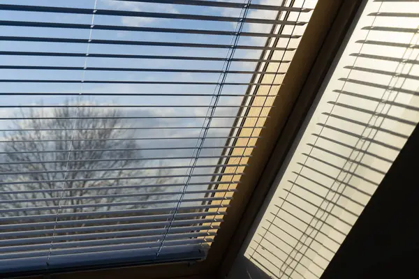 Mavi gökyüzünün önündeki pencerenin yarısı açık.