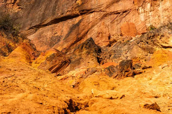 Terk edilmiş bir boksit madeninde parlak turuncu renklerle erozyona uğramış bir kayalık oluşumu.