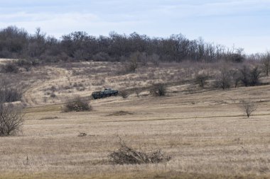 Old soviet BTR-80 armored personnel carrier in green camouflage is driving on a barren winter hill clipart