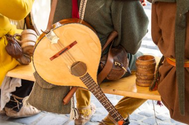 Medieval musicians sitting on a bench with a traditional lute and wooden tankard clipart