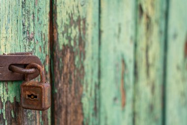 Eski paslı asma kilit, eski yeşil, boyanmış ahşap yüzey arkaplan dokusu.