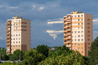 Renkli 10 katlı panelli evler, Macaristan 'daki konutlar. Arka planda kara fırtına bulutları var.