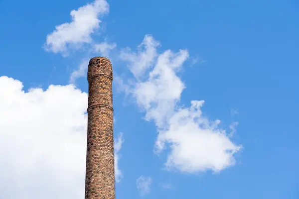 Bulutlu mavi gökyüzünün önündeki eski harap tuğla baca