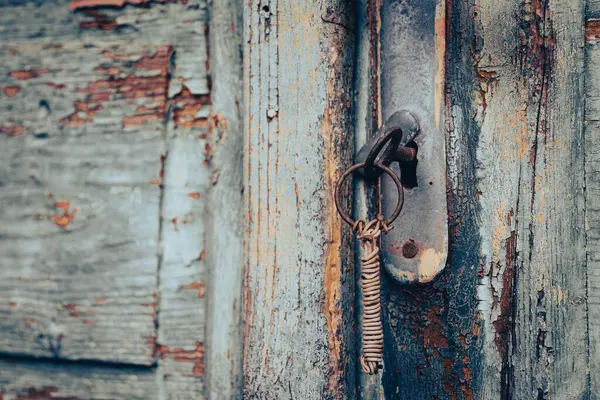 Paslı bir anahtarı olan eski bir kilit ve aşınmış yeşil ahşap bir yüzey.
