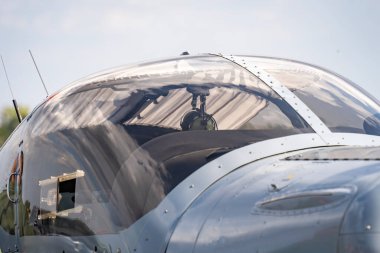 Çimenli bir havaalanında gri bir askeri eğitim uçağının kokpiti.