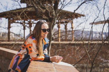 Budapeşte 'de güneş gözlüklü, renkli ceketli genç bir kadın.