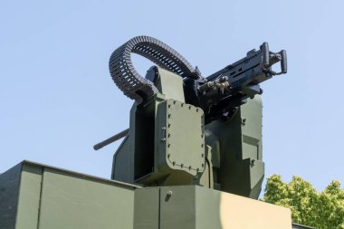 Eski klasik ağır makineli tüfek modern yeşil kamuflaj renkli zırhlı aracın tepesinde.