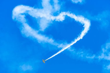 Aerobatik uçak mavi gökyüzünde kalp şekli çiziyor  