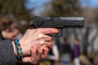 Siyah otomatik tabanca taşıyan bilezik takan bir kadın.