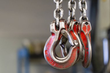 Endüstriyel zincirler ve eski püskü kırmızı boyalı kancalar.