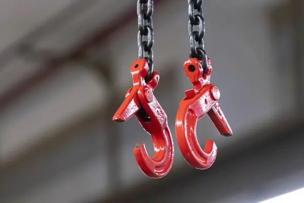 Endüstriyel zincirler ve eski püskü kırmızı boyalı kancalar.