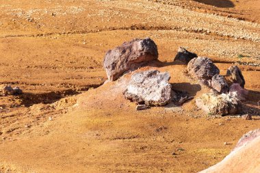 Terk edilmiş bir boksit madeninde parlak turuncu renklerle erozyona uğramış bir kayalık oluşumu.