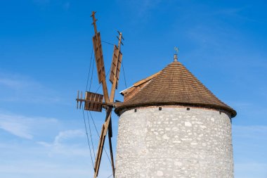 Arka planda mavi gökyüzü olan taştan yel değirmeni.